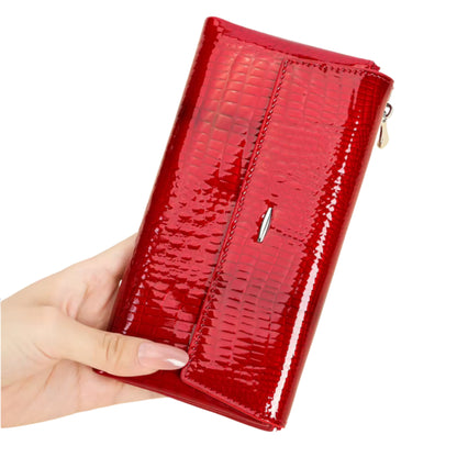 Red patent leather wallet held by a hand on a white background