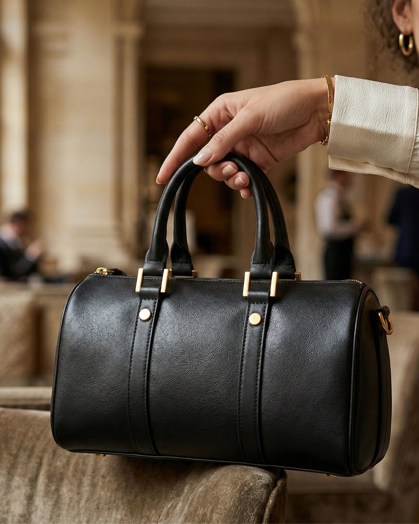 Black leather handbag held by a person in an indoor setting